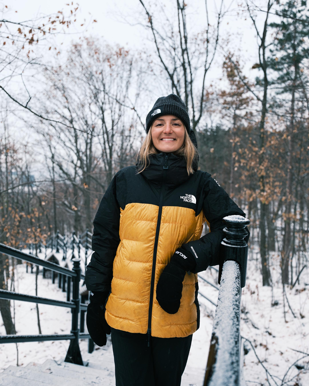 Person wearing a black and yellow winter jacket in a snowy forest